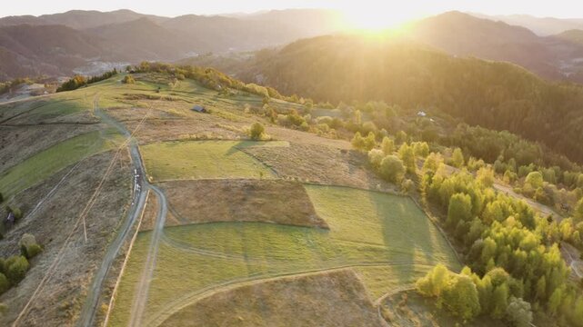 Ukraine, drone, flight in the Carpathians early in the autumn morning at sunrise near the city of Kosiv. Bright forests and dwellings of the Hutsul highlanders on the glades