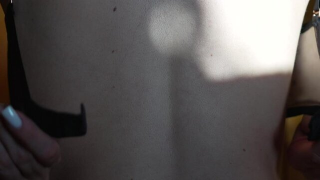 Skin back bra. A woman's bare back with hand adjusting strap, close up with copy space.
