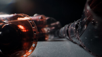 An old twisted color film lies on a dark background, symbolizing memories on the film. The film...
