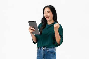 Cheerful young Asian woman holding digital tablet with fists clenched celebrating victory...