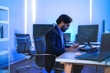 Focused Indian male AI developer coding a complex machine learning algorithm late at night. A...