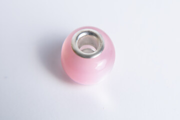 Elegant pink glass bead with metallic core resting on a smooth white surface for jewelry crafting
