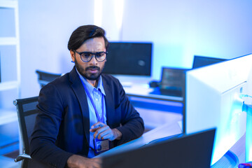 Focused Indian male AI developer coding a complex machine learning algorithm late at night. A...