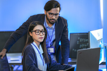 Asian female AI programmer and Indian male data analyst reviewing code on a monitor. Diverse tech...