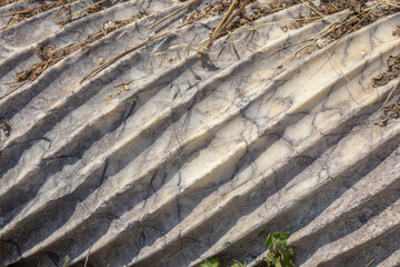Spiral sculptural relief on the surface of a column in the ancient city of Perge in Turkey. Antique columns subject to erosion and ruins of an ancient city. Background of the column surface.