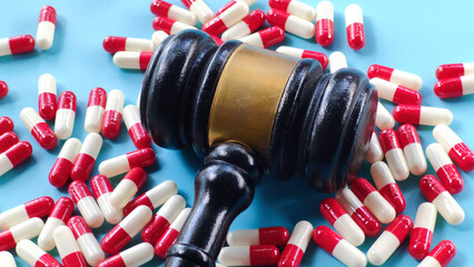 Gavel and Red and White Capsules on Blue Background