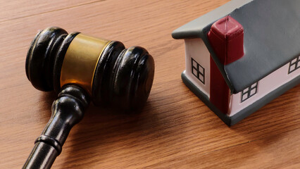 Gavel and Miniature House on Wooden Table
