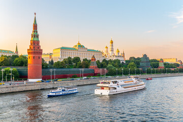 Obraz premium View of Kremlin with Vodovzvodnaya tower, Grand Kremlin Palace from repaired Bolshoy Kamenny Bridge in Moscow city on sunny summer day. Cruise ship sails on the Moscow river