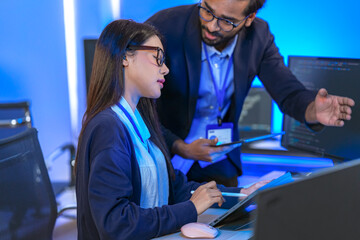 Asian female AI programmer and Indian male data analyst reviewing code on a monitor. Diverse tech...