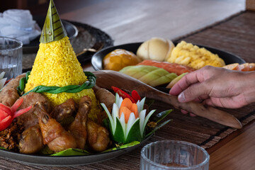 A beautifully plated traditional Indonesian dish featuring Nasi Tumpeng, a cone-shaped rice centerpiece surrounded by various savory side dishes. This festive dish symbolizes gratitude, celebration.
