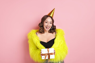 Birthday celebration. Woman with gift on pink background