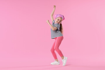Cute little girl dancing on pink background
