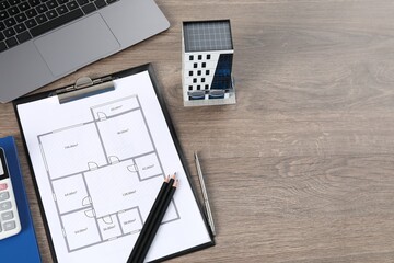 Real estate. Apartment building model, floor plan and laptop on wooden table, above view. Space for...