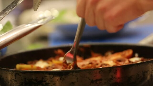 Chef stirs seasoned minced meat. Stuffed pasta shells with meat filling simmer in bubbling tomato sauce. This hearty, delicious Italian meal is perfect for a family dinner.