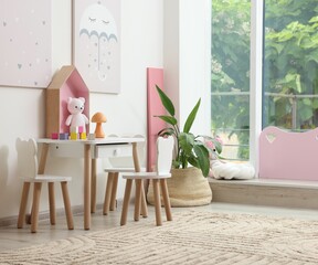 Stylish playroom with toys and furniture near window. Interior design