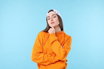 Portrait of beautiful woman in stylish baseball hat on light blue background