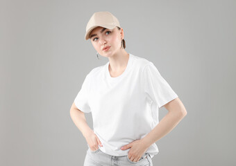 Beautiful woman in stylish baseball hat on grey background