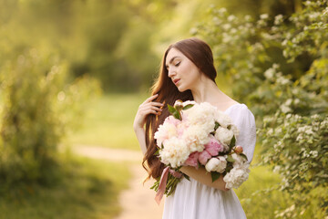 Naklejka premium Beautiful woman with bouquet of peonies in park. Space for text