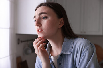 Worried woman suffering from paranoia in kitchen