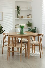 Wooden table, chairs, tulips and green houseplants indoors. Interior design