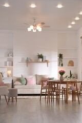 Stylish dining table with chairs and comfortable sofa in room. Interior design