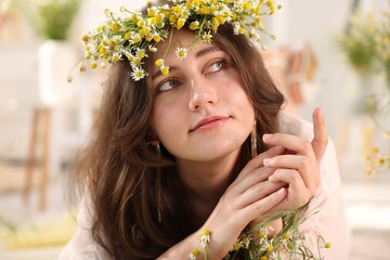 Portrait of beautiful woman with chamomile flowers indoors