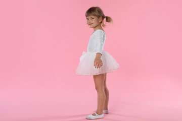 Cute little girl dancing on pink background