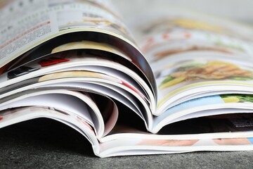 Different open magazines on grey table, closeup