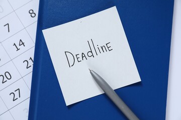 Sticky note with word Deadline, notebook, pen and calendar on table, top view