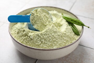 Protein powder and green peas on light tiled table, closeup