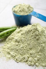 Protein powder and green peas on light tiled table, closeup