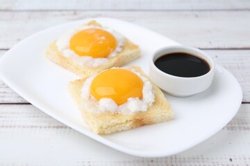 Fototapeta premium Tasty kaya toasts with half-boiled eggs served on white wooden table, closeup. Traditional asian breakfast