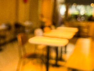Intentionally blurred image of a cozy cafe interior with warm ambient lighting and bokeh effect, showing tables, chairs, and a relaxed atmosphere. Ideal for background or design use.

