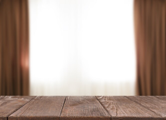 Empty wooden table against window with curtains in room