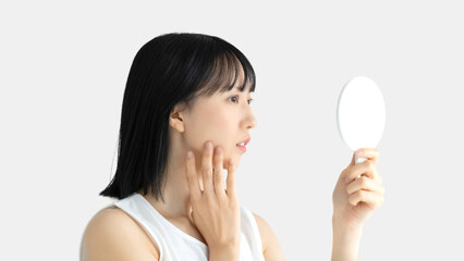 鏡で肌をチェックする若い女性