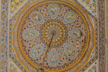 View of an ornate ceiling with detailed concentric patterns and figures in circular frames, showcasing cultural artistry, Bikaner, Rajasthan, India.