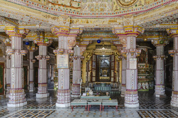 View of intricately carved pillars and a dazzling, ornate interior of a temple, bathed in soft light and rich colors, Bikaner, Rajasthan, India.