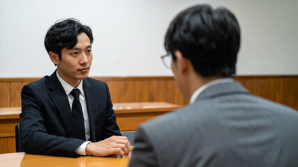 Two businessman in formal attire in an interview setting at a table 