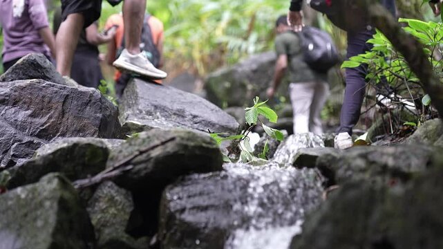 Backpackers hiking on fresh mountain water cascading off a rocky cliff in Karnataka's Western Ghats