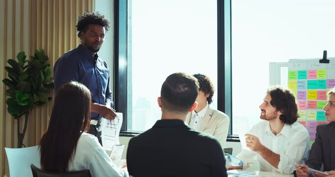 Creative professional presenting mobile UX/UI wireframes to a diverse team during a brainstorming session, promoting collaboration and innovation in a modern office setting. - Powered by Adobe