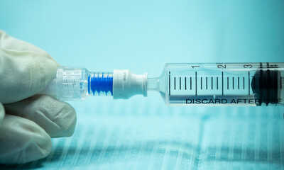 Close-up of syringe inserted into a non-return cap with visible internal spring compressed. Part of...