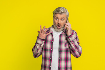Mature man speaks on mobile phone with forceful tone, revealing anger agitation during tense talk...