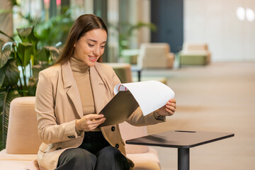 Caucasian young businesswoman working with documents, analyzing information, reading papers prepare...