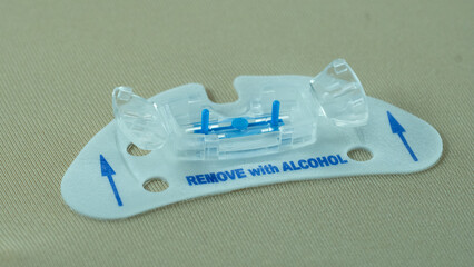 Side view of a STATLOCK adhesive securement device applied to simulated skin. The catheter holder...