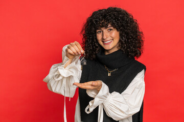 Caucasian young woman with curly hair real estate agent lifting hand showing the keys of new home...