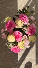 Bright bouquet of pink and cream roses top view, with sunlight and shadows. Festive and cozy mood.