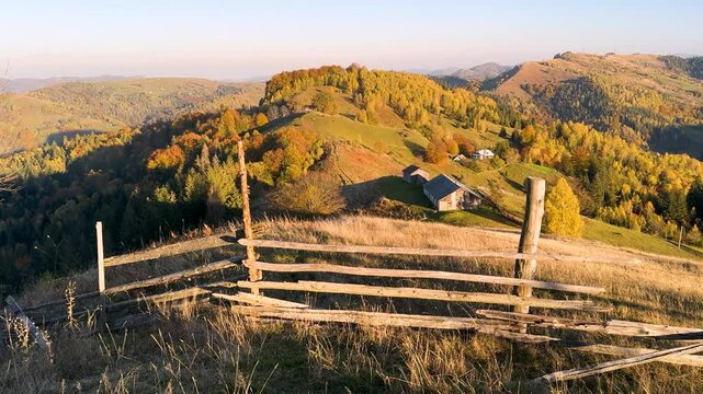 Ukraine, drone, flight in the Carpathians early in the autumn morning at sunrise near the city of Kosiv. Bright forests and dwellings of the Hutsul highlanders on the glades