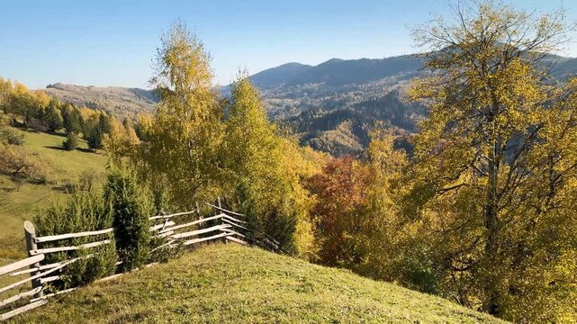 Ukraine, drone, flight in the Carpathians early in the autumn morning at sunrise near the city of Kosiv. Bright forests and dwellings of the Hutsul highlanders on the glades