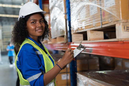 Warehouse, worker and working concept. Female warehouse worker checking barcodes and product name on boxes on shelf pallet in warehouse