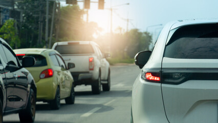 Rear side of white car with turn n brake light. Stop at a traffic light at an intersection. Traffic congestion during rush hou in the suburbsr. Roads in Thailand during daytime.